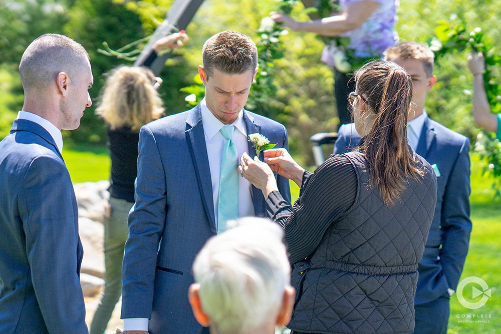 wedding planner assisting groomsmen with boutonnière flower