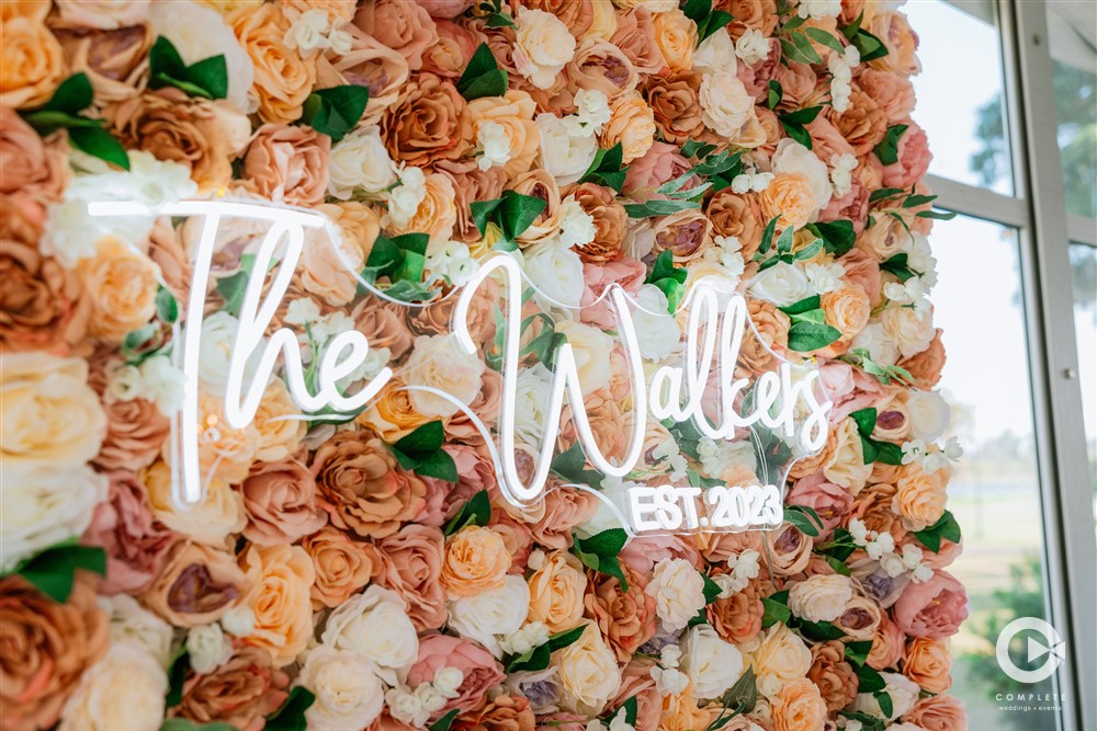 flower wall at wedding with neon sign