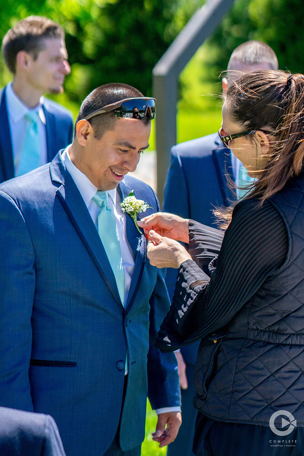 wedding planner assisting groomsmen with boutonnière