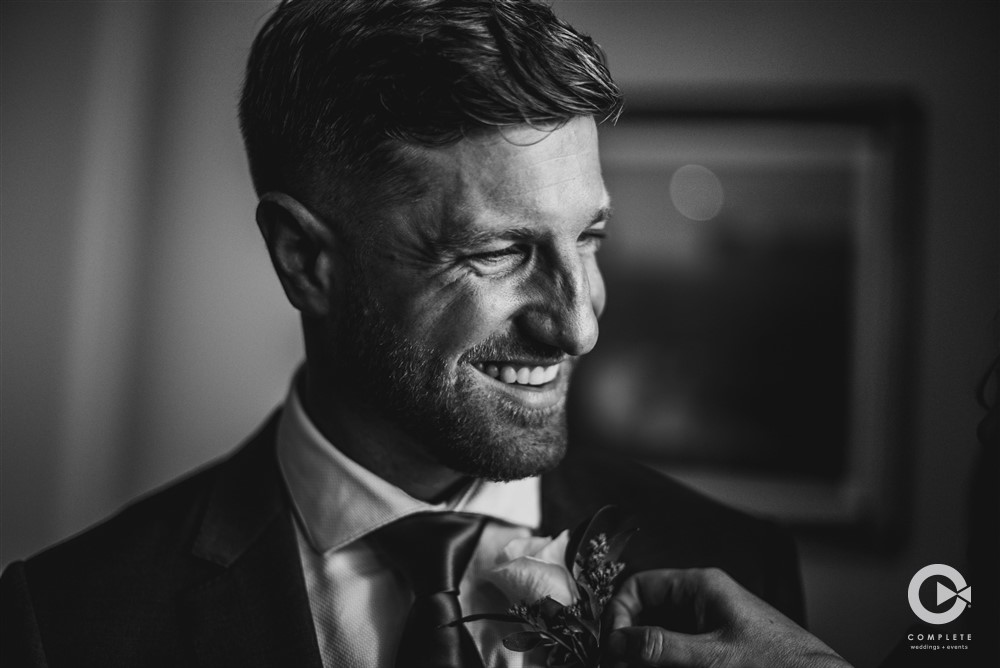 a groom getting his boutonniere pinned on