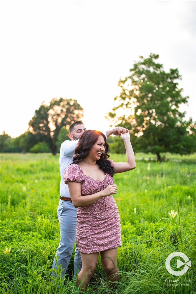 newly engaged couple dancing in field