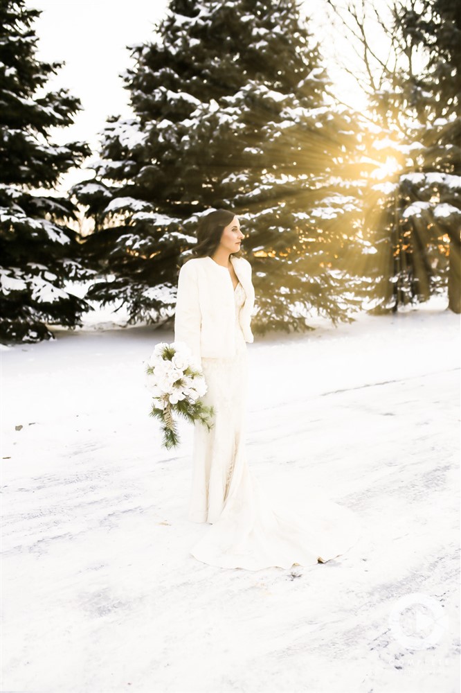 Gorgeous bride standing outside in the snow during January wedding as the sun sets