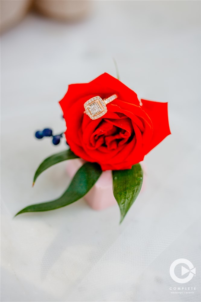Bright red wedding flower with a wedding ring sitting in the pedal