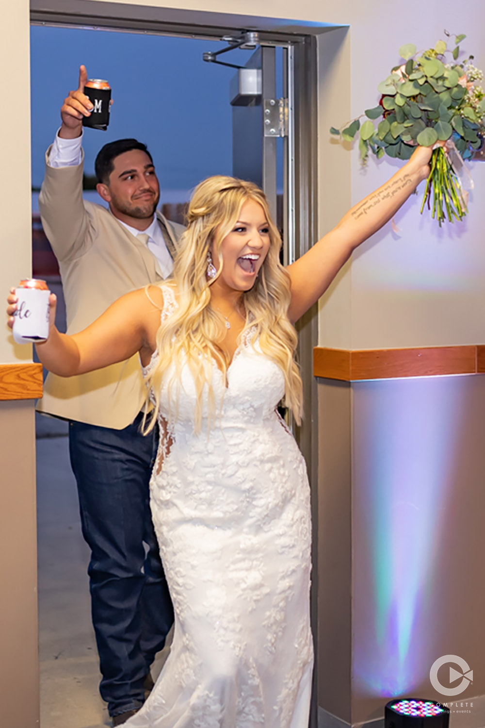 Bride raising her bouquet while entering reception in Brainerd, MN