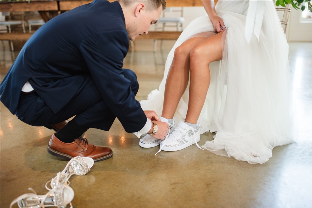 groom putting on brides reception shoes