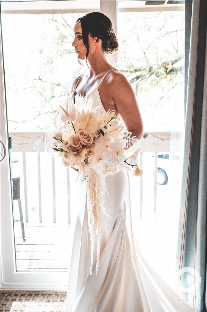 bride standing in front of window in simple white dress