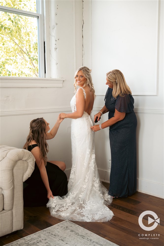 Complete Weddings + Events Photography, bride with her mom on her wedding day, mom zipping up bride into her wedding dress