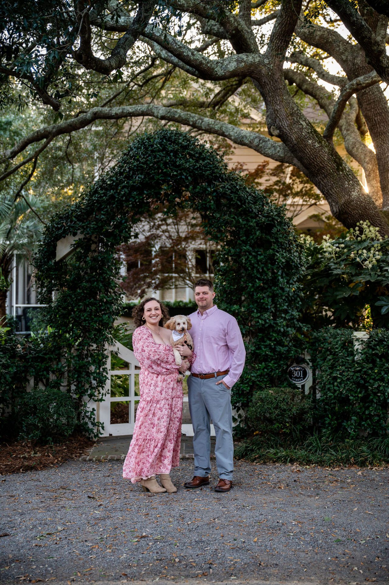 Couple posing beneath a romantic ivy-covered arch during an engagement session in Charleston, South Carolina. Timeless Lowcountry engagement photography surrounded by historic oak trees and natural greenery.