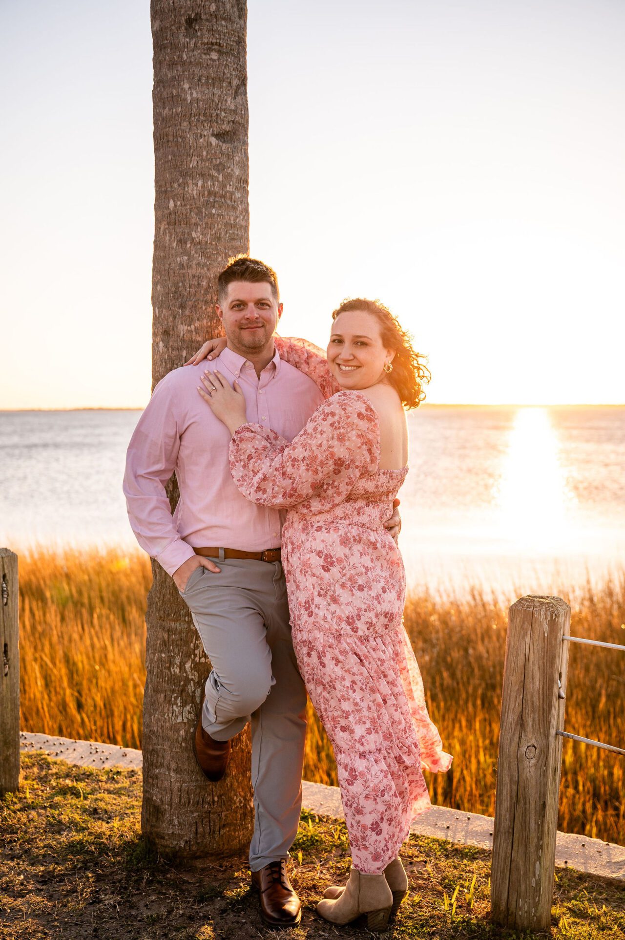 Couple posing together during a romantic sunset engagement session in Mount Pleasant, South Carolina, beside the marsh waterfront with glowing golden hour light and Lowcountry scenery.