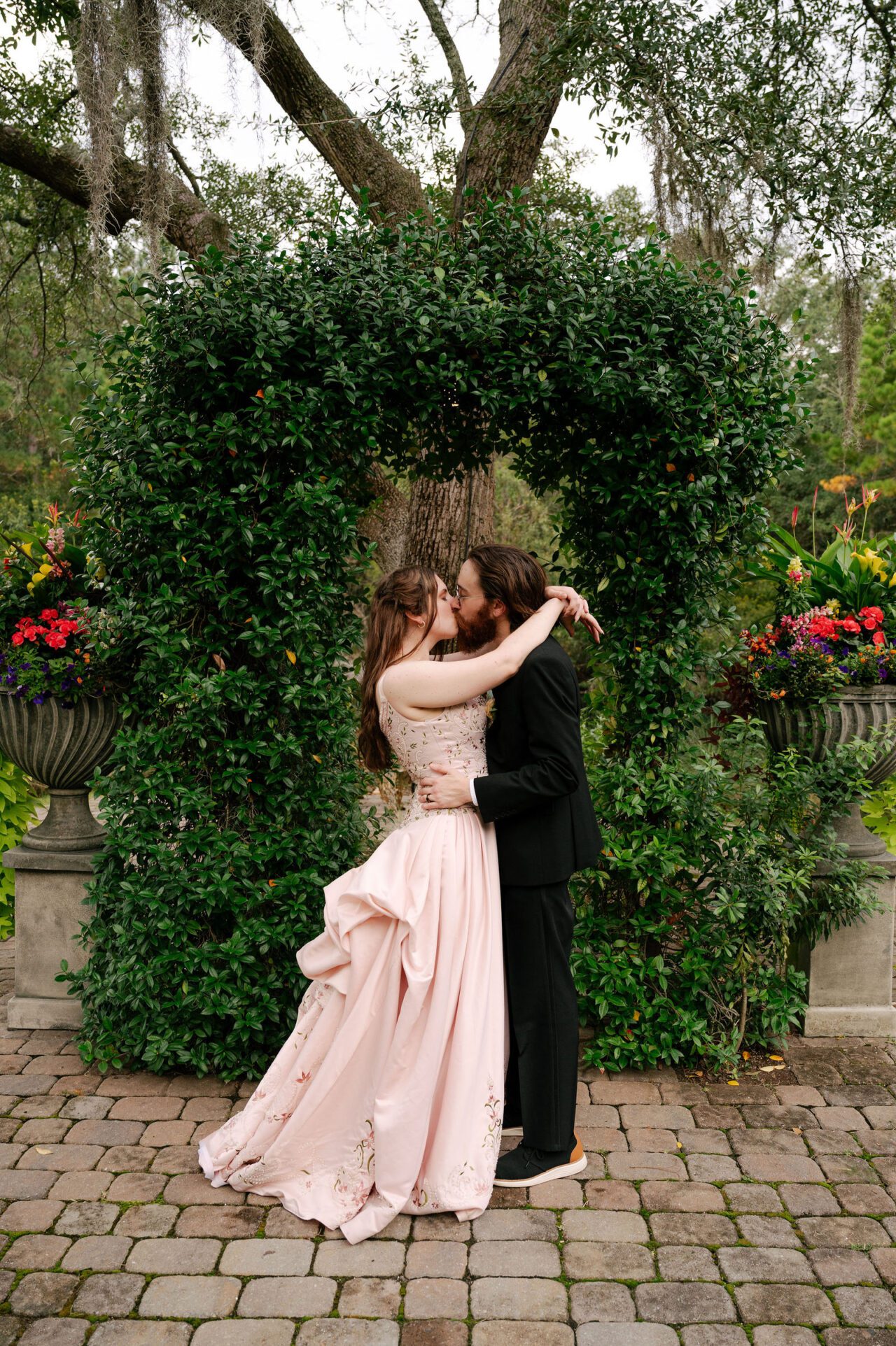Bride and groom sharing a romantic outdoor wedding moment surrounded by greenery and elegant black and white decor. Charleston wedding photography portrait with timeless, cinematic style.