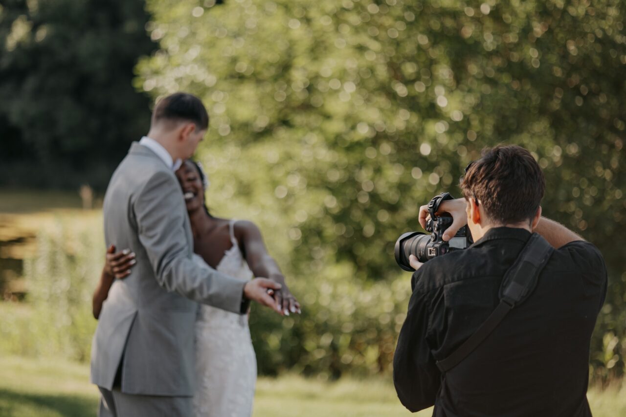 Videographer filming a bride and groom outdoors