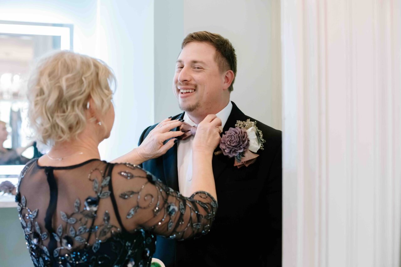 Groom and mom fixing bowtie for wedding at Dunes West Golf Course & River Club