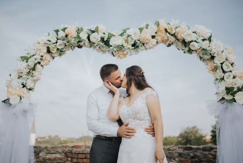wedding arch with flowers with a couple underneath it