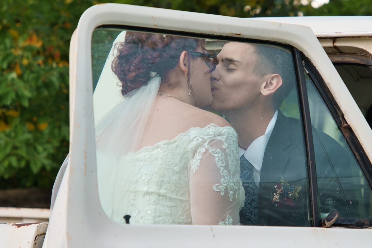 Bride and Groom hide behind window to sneak a kiss. Michael Evans is the wedding photographer for this photo.