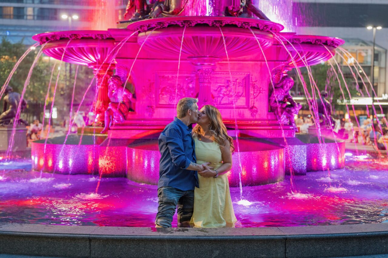 Couple in the kissing while in the fountain at Fountain Square in Downtown Cincy. Michael Evans is the wedding photographer who took this photograph.