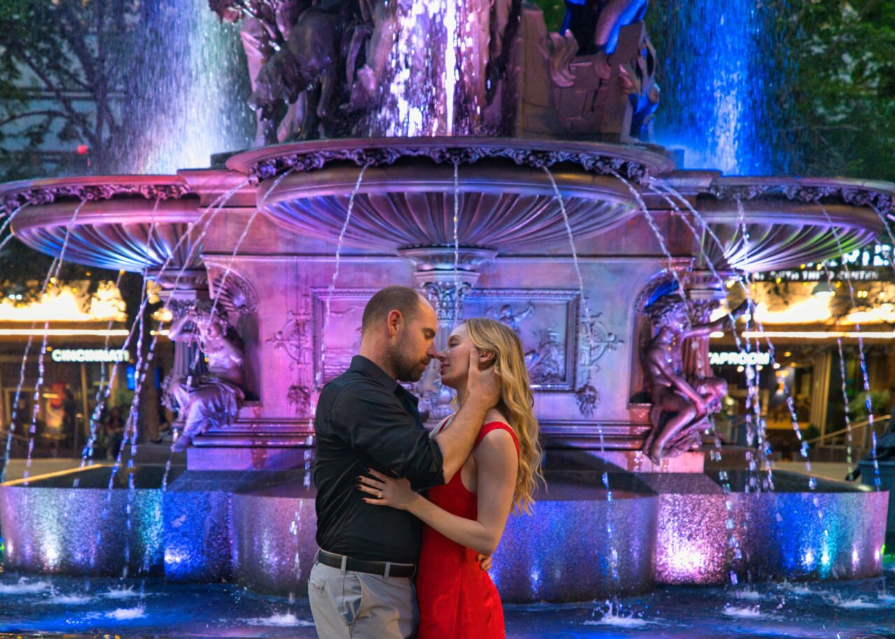 Engagement shoot at Fountain Square in downtown Cincinnati as the couple embraces. Photography credit goes to Michael Evans.
