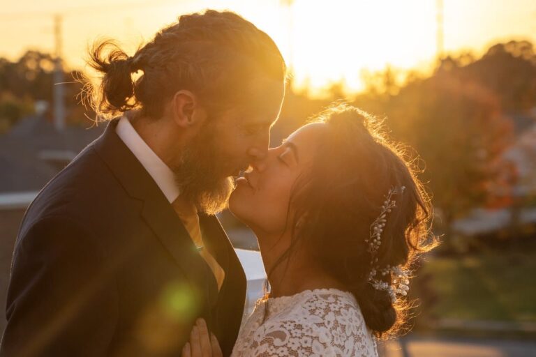 Bride and Groom kiss as sunsets behind them. Complete Weddings and Events photographer Michael Evans took the photo.