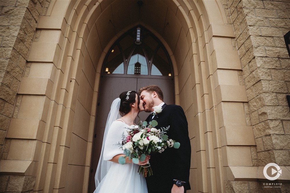 Amazing shot of bride and groom kissing in front of wedding chapel in Colorado