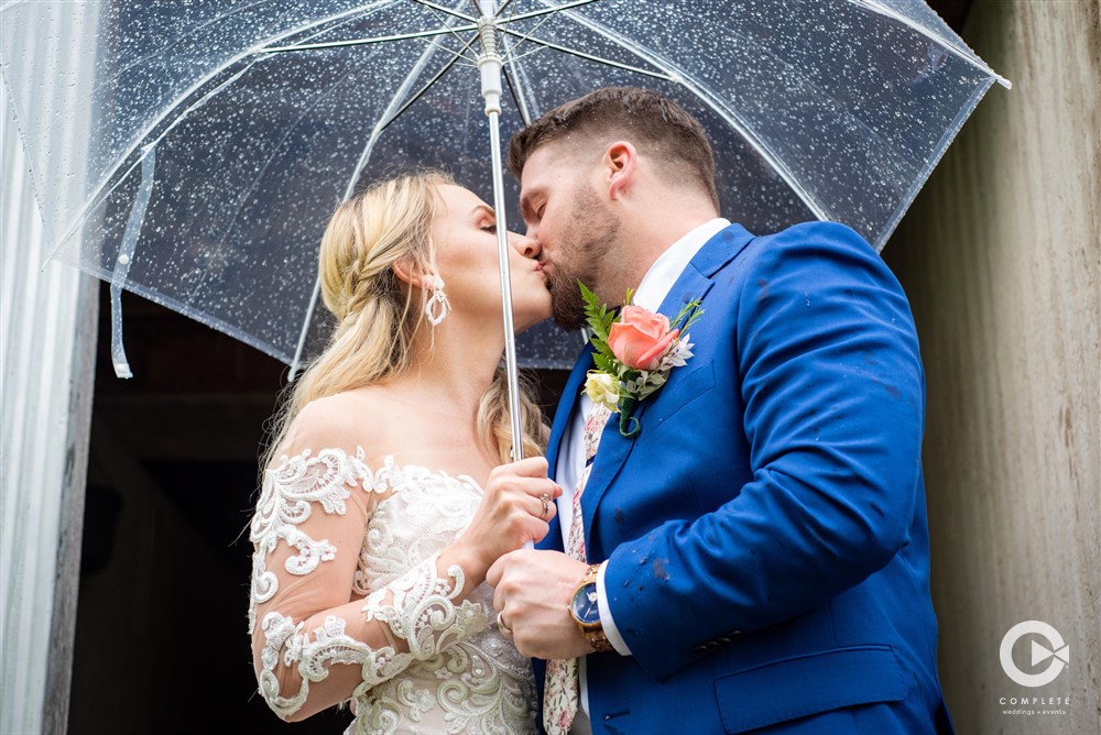 Complete Weddings + Events Photography, bride and groom kissing, rainy wedding day wedding portraits