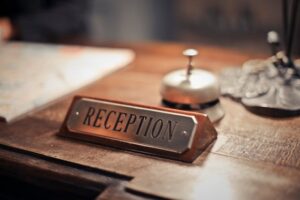 reception desk featuring a metal nameplate with "RECEPTION" engraved, placed on a wooden surface
