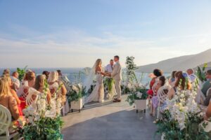 outdoor wedding ceremony on a terrace overlooking the ocean and mountains during sunset