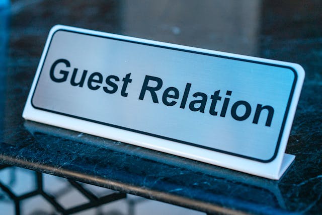 desk nameplate with black text reading Guest Relations