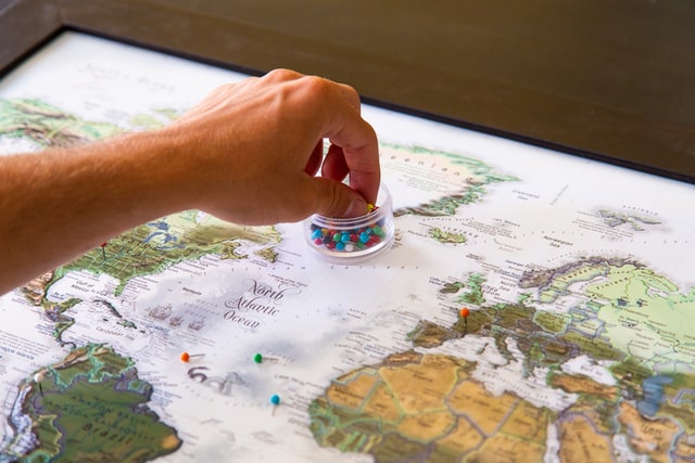 Person pinning places on a world map.