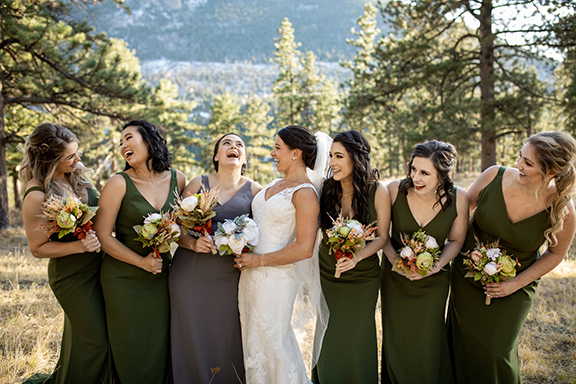 Bride and Bridemaids laughing with mountains and tree behind them