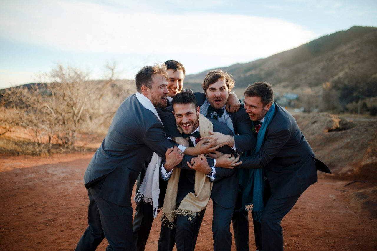Candid photo of groomsmen hugging the groom