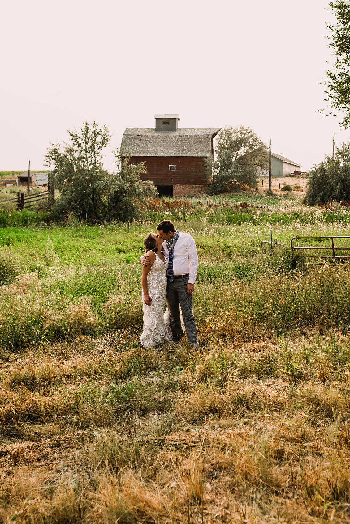 Bride and groom kissing in the field in front of their wedding venue
