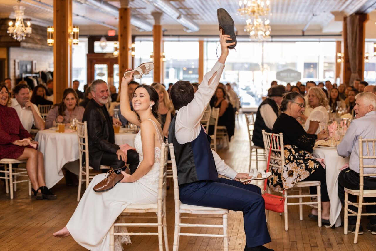 Bride and groom having fun with shoe game, while audience enjoys the ensuing fun