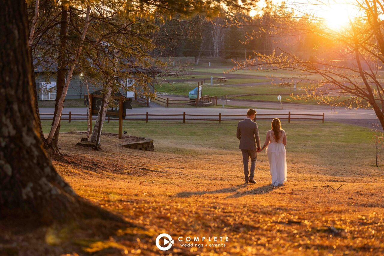 Bride and Groom walk down hill at Buffalo House during Sunset