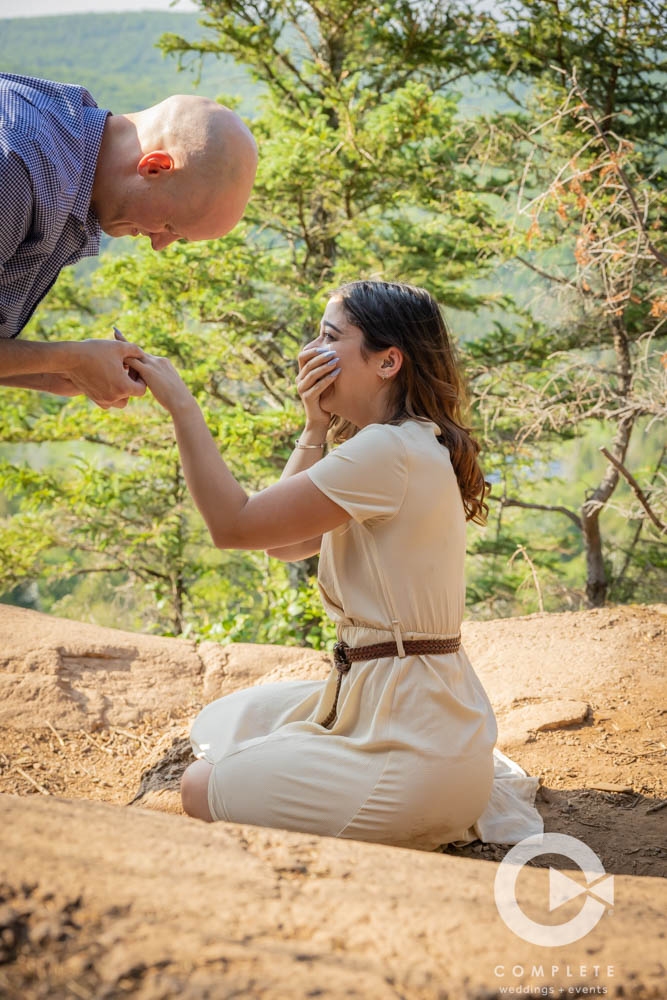 Adam placing ring on Nicoles finger after proposal