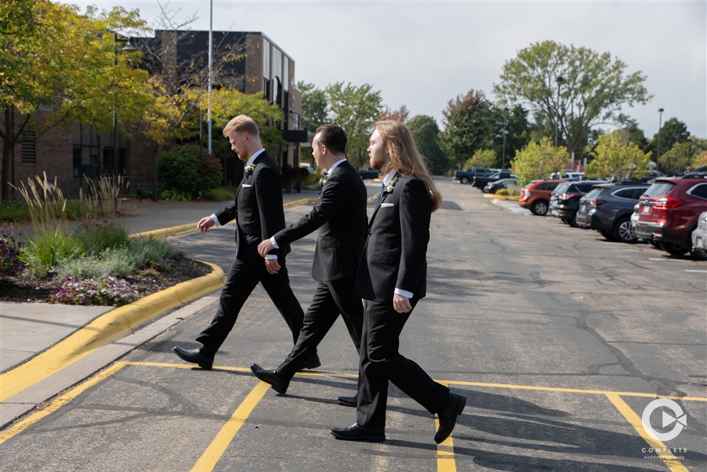 Groomsmen crossing the walkway in classic Beatles Fashion photo captured by Complete Weddings + Events