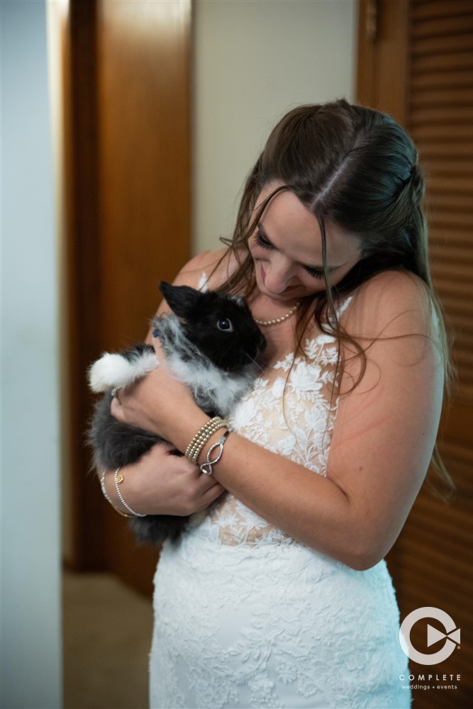 Bride holding bunny in wedding dress photo taken by Complete Weddings + Events