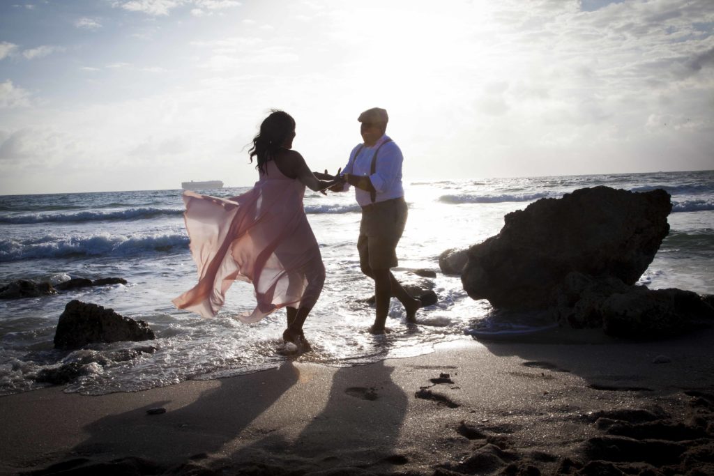 man and woman holding arms and dancing on the beach