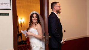 Bride and Groom back to back at The Signature Grand. Bride is smiling and reading a paper