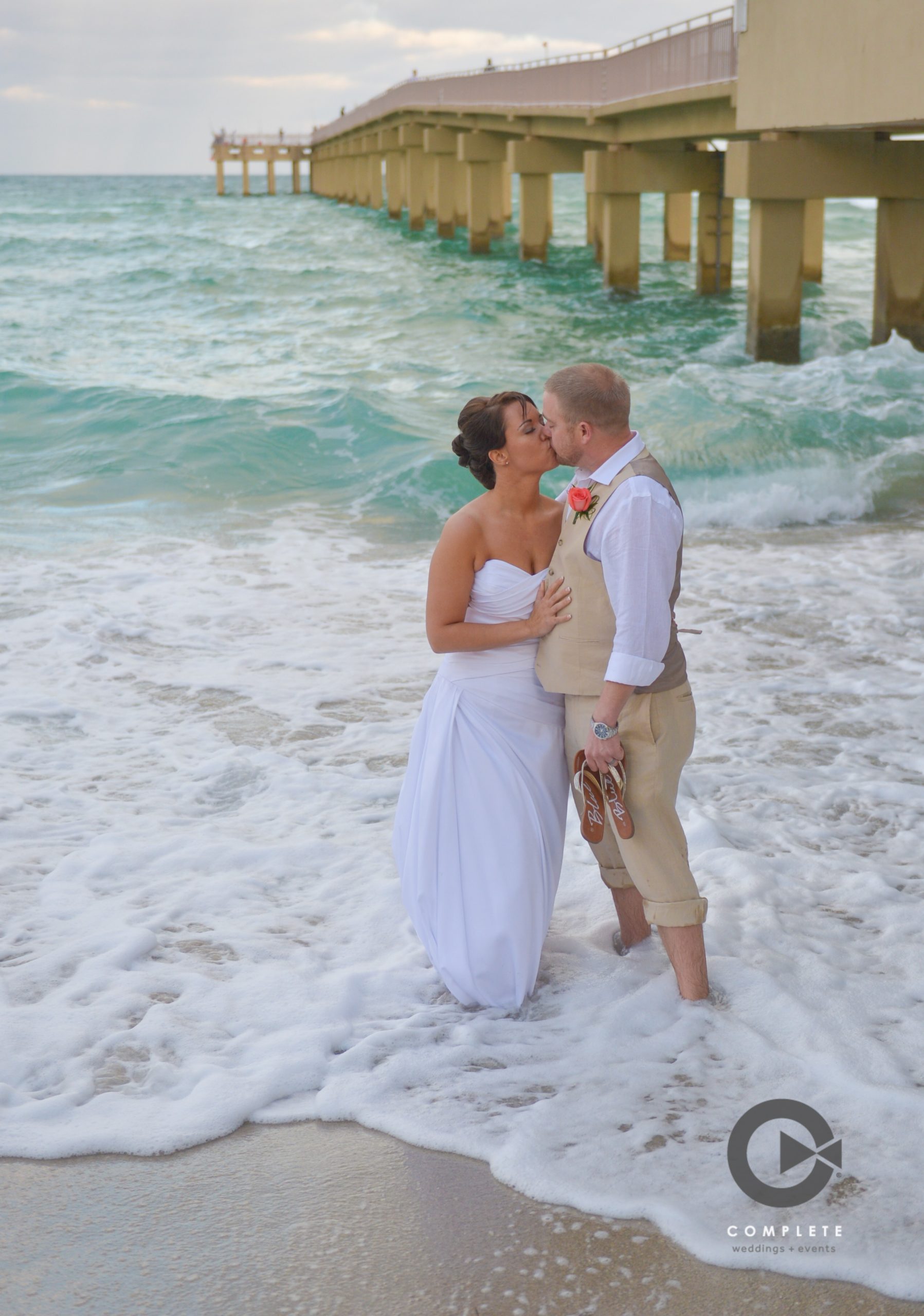 Bride and groom kissing on the beach on the pier