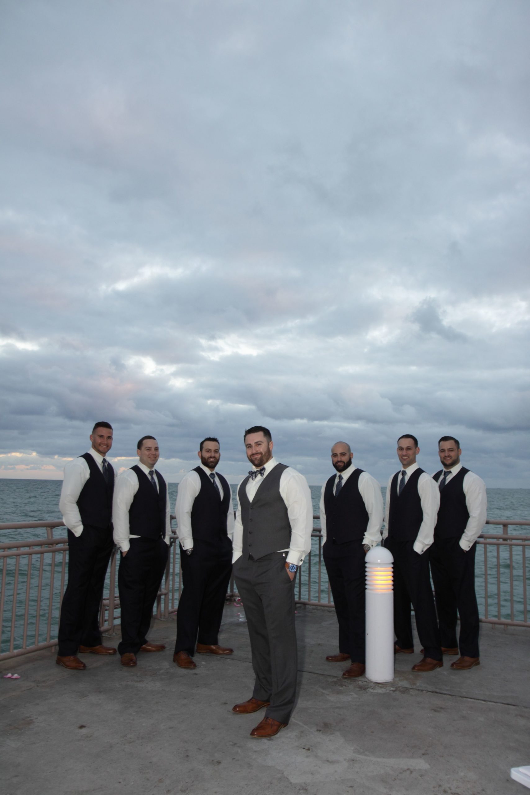 seven men posing on a dock with the sky as the backdrop