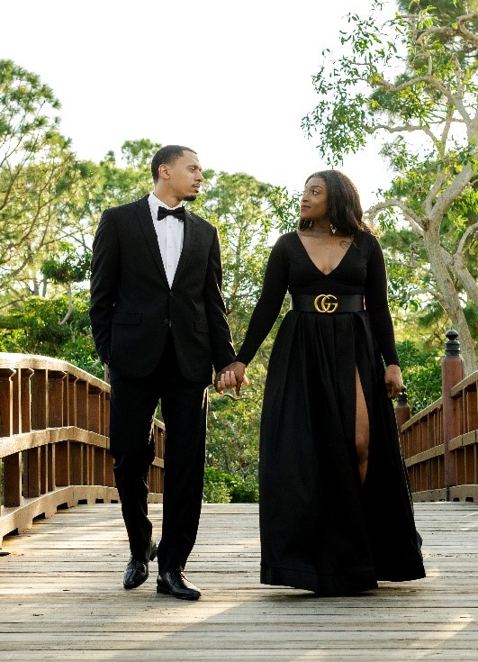 African American couple holding hands, wearing black and walking on a bridge