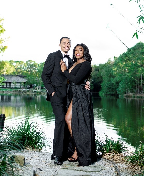 African American couple holding hands, wearing black and standing in front of a lake