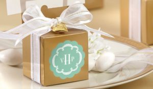 Gold gift box with white ribbon with monogram showing 3 letters VHP