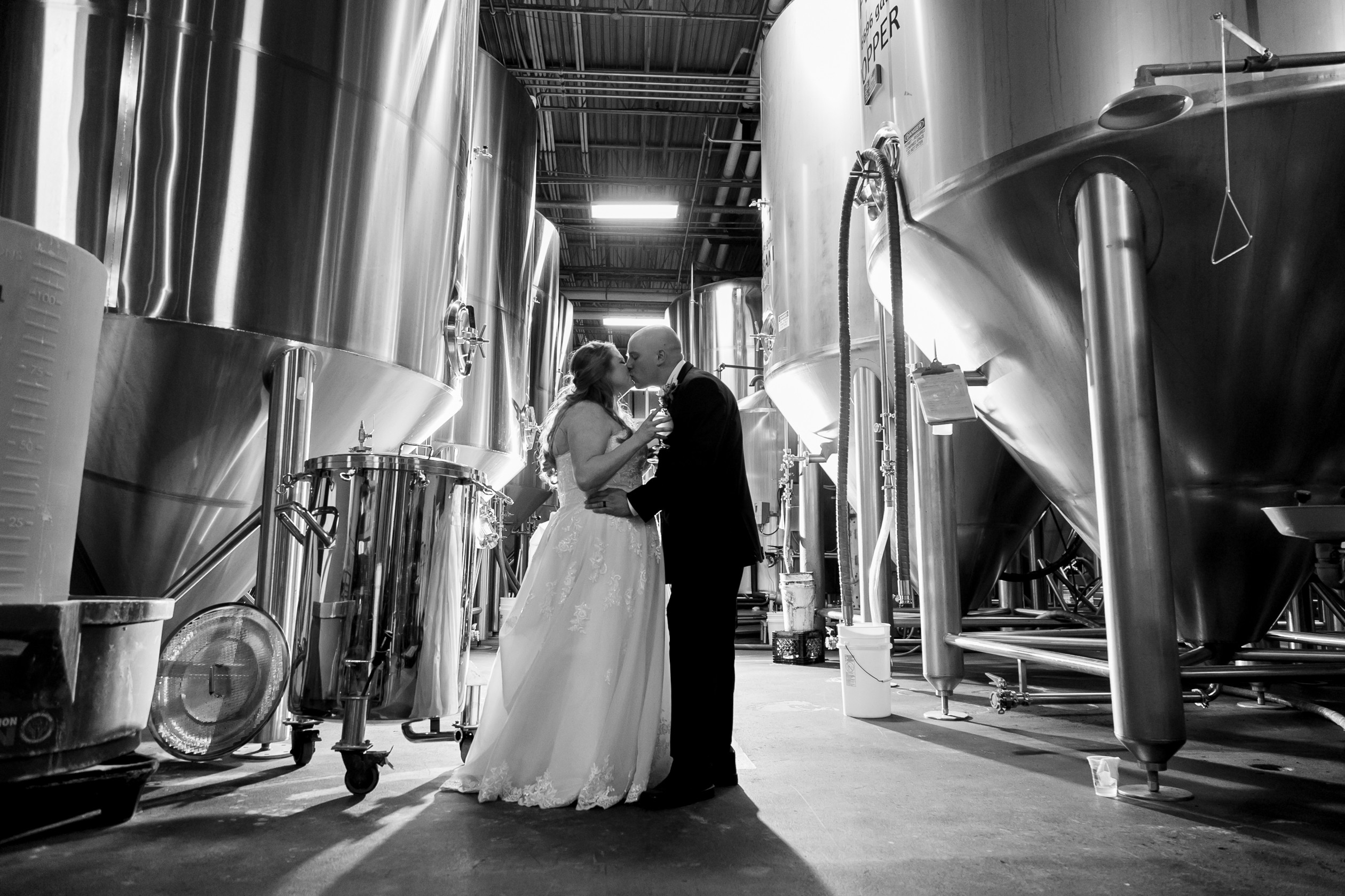 Bride and Groom kissing in front of distillery at Funky Buddha Brewery
