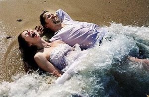 Trash the dress - bride and groom laying in the sand