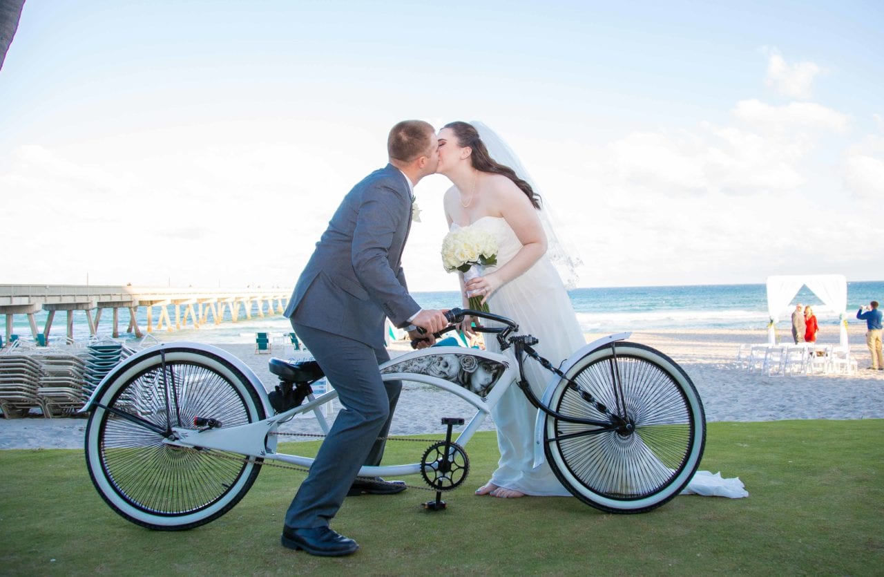 Bride and groom on a bicycle at the beach