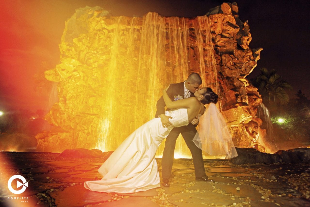 Bride and groom kissing in front of waterfall