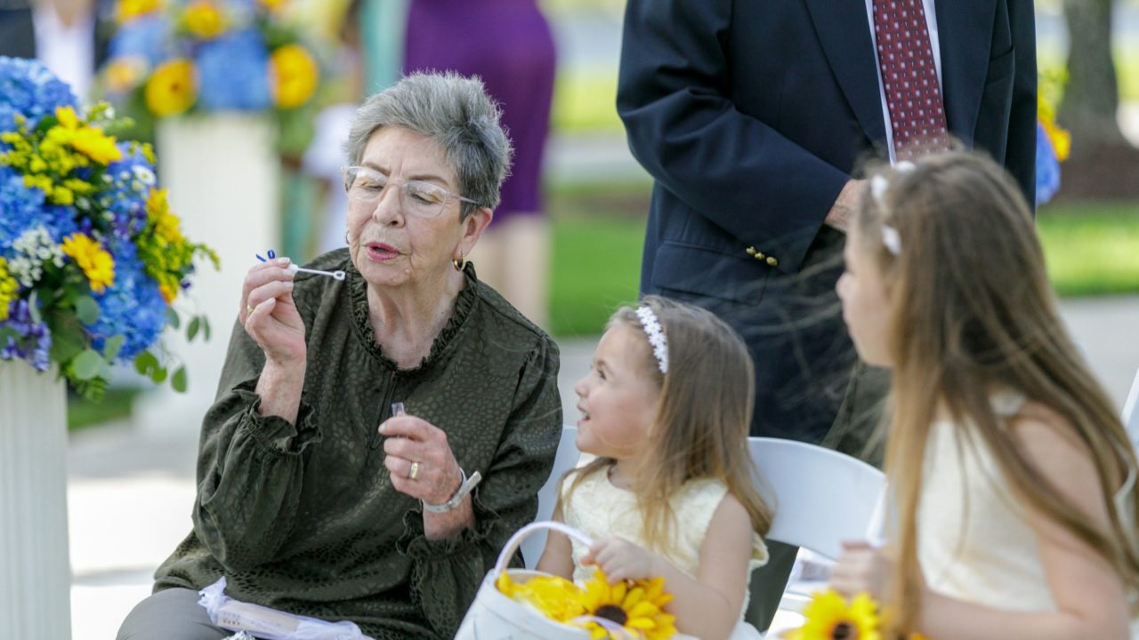 Mother of the bride and flower girls blowing bubbles at wedding ceremony