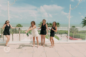 Bride with bridesmaids pop open the champagne at Sundial Beach Resort and Spa wedding