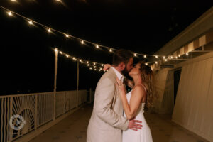 Bride and Groom kiss under string lights at Sundial Beach Resort and Spa wedding