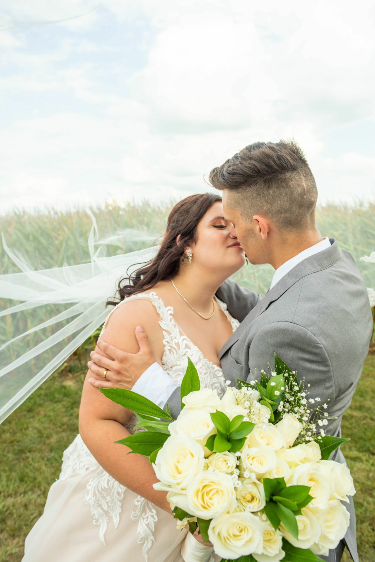 Bride and groom kiss with veil overtop